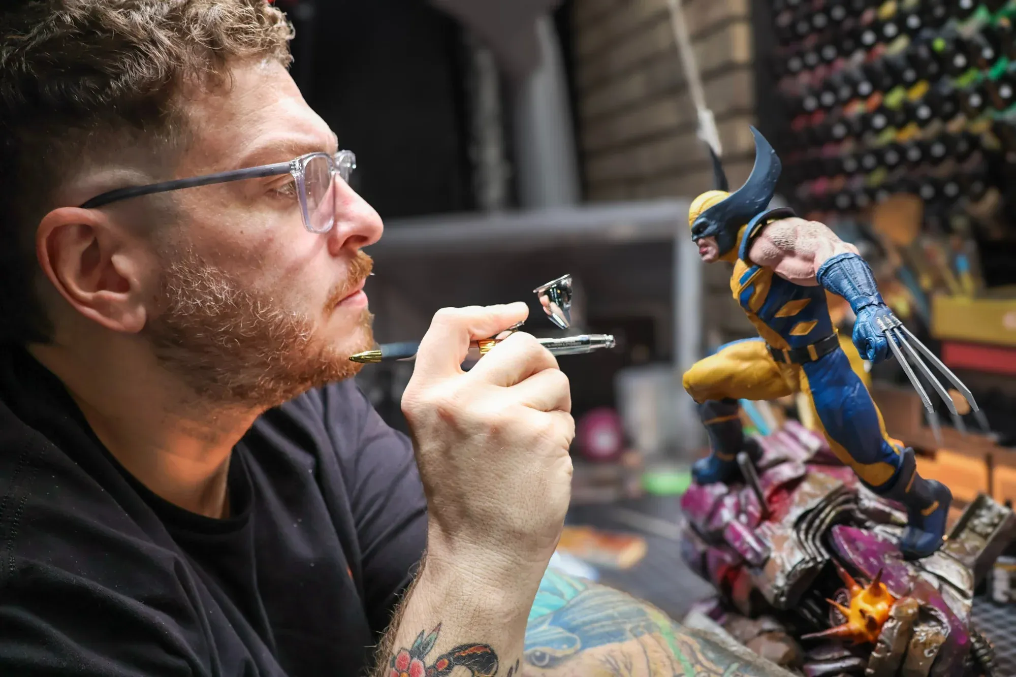 Ryan airbrushing a hand-painted Wolverine statue in the shop.