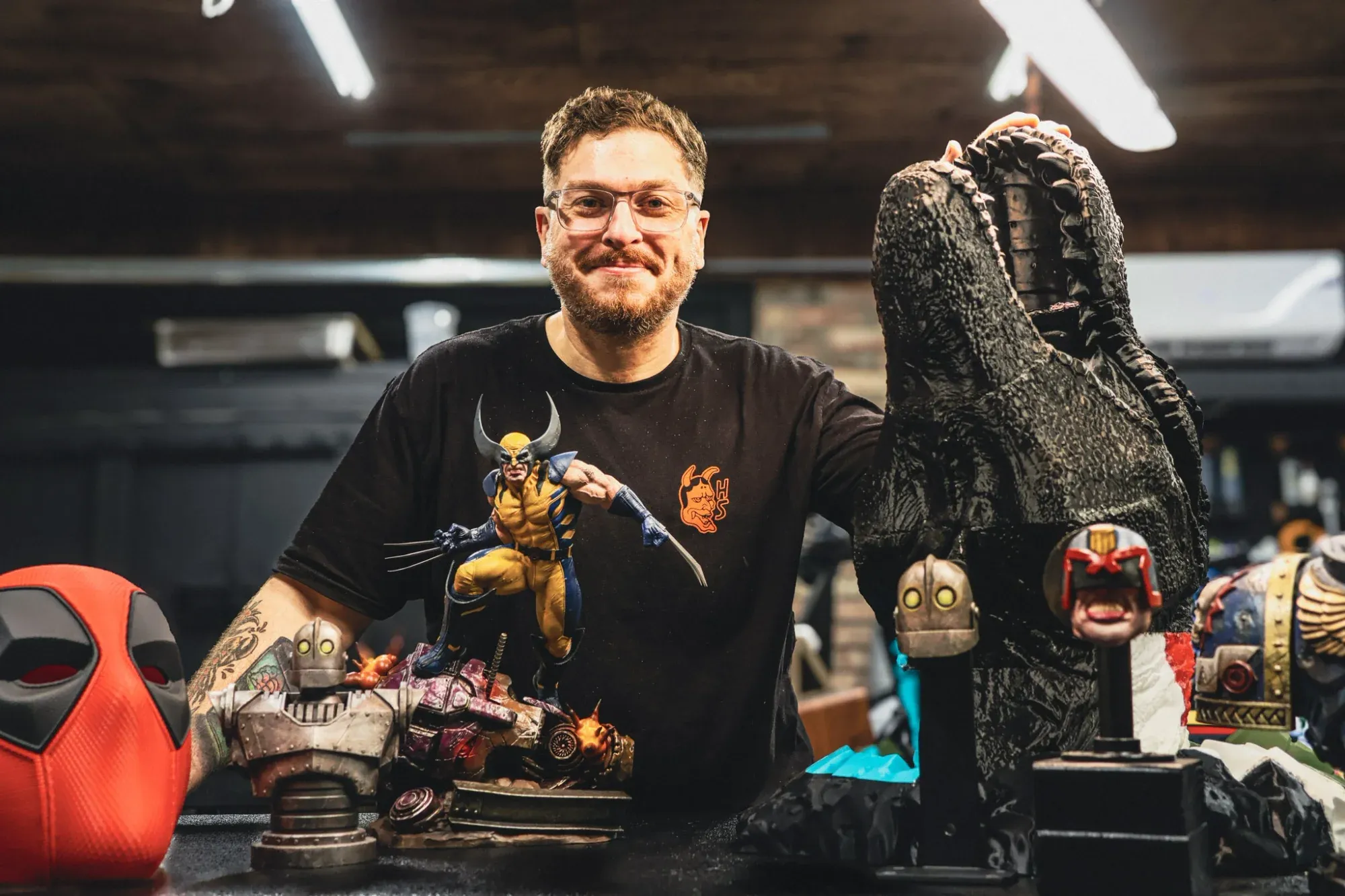 Ryan McHenry in the shop, smiling behind a lineup of his hand-painted statues and busts.