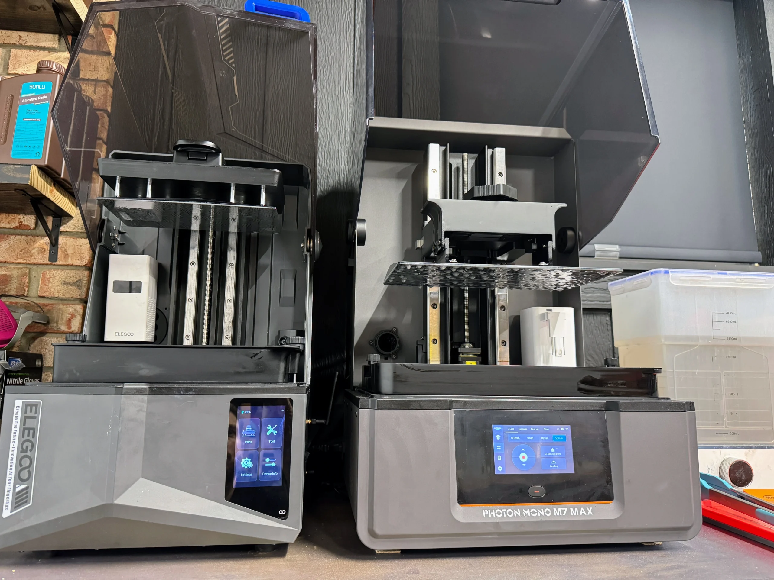 A sleek shelf with resin 3D printers, curing stations, and display tools for miniature production.